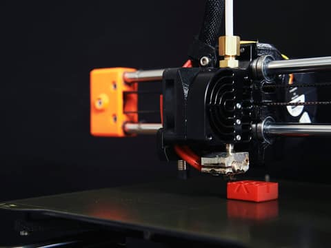 Imprimante 3D fabriquant une petite pièce rouge