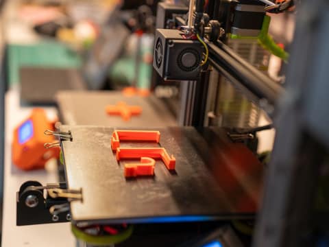 Pièce orange en cours d impression sur un plateau d imprimante 3D